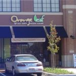 Storefront of Orange Leaf Self Serve Frozen Yogurt with black awnings and logo sign on building