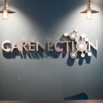 Carenection wall sign indoors above a desk