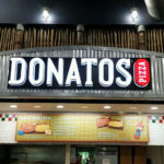 Donatos Pizza logo neon sign above ordering counter in restaurant